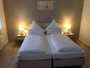 two beds in a room with two lamps on tables at Hotel Gambrinus Dutenhofen in Wetzlar