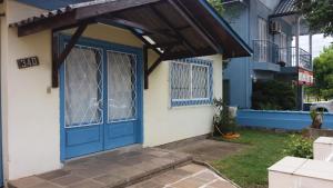 eine blaue Tür an einem Haus mit Markise in der Unterkunft Casa da Vó Nelsi in Gramado