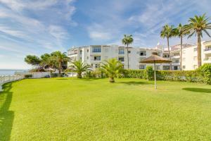 a large lawn in front of a building with palm trees at Apartamento Las Palmeras in Nerja