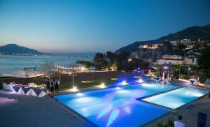 a large swimming pool with a view of the water at night at Residence Le Axidie in Vico Equense
