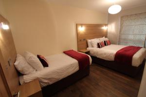 una camera d'albergo con due letti e uno specchio di Maryville Apartment by Townlets a Belfast