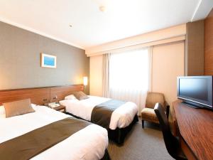 a hotel room with two beds and a flat screen tv at Alpico Plaza Hotel in Matsumoto
