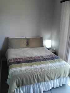 a bed in a bedroom with a lamp on a table at Forest Cove cottage in Knysna