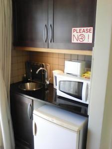a small kitchen with a microwave and a sink at Forest Cove cottage in Knysna