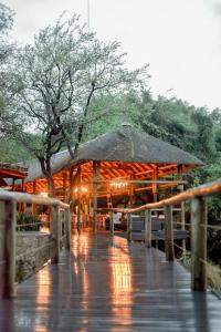 a pavilion with an umbrella on a boardwalk in the rain at Moditlo River Lodge in Hoedspruit