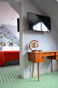 um quarto com uma secretária e uma televisão na parede em Hotel Les Pilotes em Saint-Valery-sur-Somme