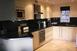 een keuken met witte kasten en zwarte aanrechtbladen bij 5 Laurel Court in Ulverston