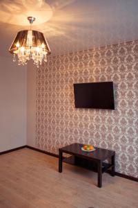 a room with a table and a television and a chandelier at Apartment Lenina in Vladimir