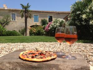 two glasses of wine and a pizza on a table at Le Coing des Vignes in Mauressargues