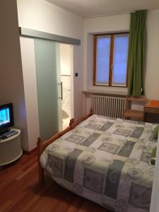 1 dormitorio con 1 cama y TV en Affittacamere Penasa, en Rabbi