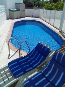 a pool with two blue lounge chairs next to it at Avra Garden Villa in Protaras