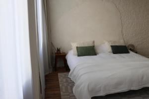 a bedroom with a white bed with two green pillows at Mañana Mañana in Antwerp