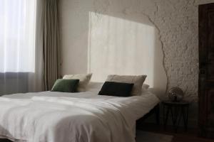 a bedroom with a white bed with two green pillows at Mañana Mañana in Antwerp