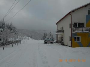 a car parked on a snow covered street next to a building at Cabana Filip in Cavnic