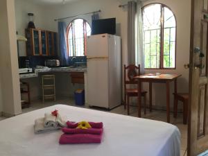 a room with a white bed with a refrigerator at La Perlita in Jacó