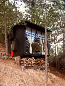 a cabin in the woods with a pile of logs at La Quinta Glamping - Lago de Tota in Cuítiva
