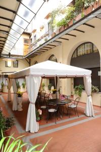 patio con tavolo e sedie sotto un ombrellone bianco di Hotel Residence La Contessina a Firenze