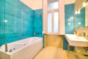 Baño azul con bañera y lavamanos en Central Stylish Apartments, en Budapest