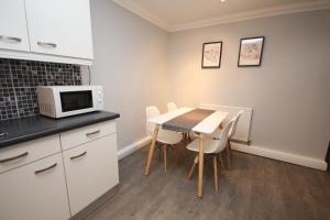 cocina con mesa, sillas y microondas en The Garden Apartment en Leamington Spa