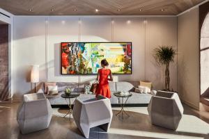 a woman walking through a living room with a painting on the wall at The James New York - NoMad in New York