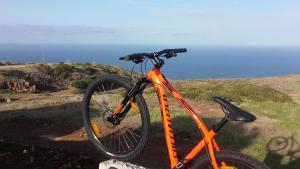 uma bicicleta laranja estacionada numa colina perto do oceano em Residencial FAROL em Ponta do Pargo
