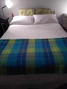 a bed with a plaid blanket on top of it at Big bright room in Carrigaline