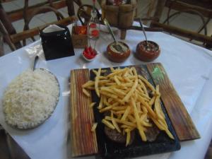 a plate of food with french fries and rice on a table at Pousada Toka do Lula in Peruíbe