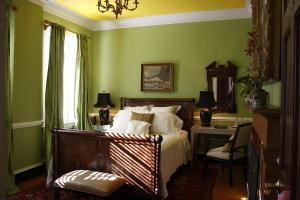 um quarto com uma cama com paredes verdes e uma secretária em Inn at Court Square em Charlottesville