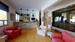 a living room with red and white chairs and a tv at Riotel Perce in Perce