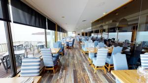 a restaurant with blue chairs and tables and windows at Riotel Perce in Perce
