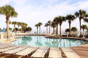 a swimming pool with lounge chairs and palm trees at Ocean Walk Resort - Remarkable Ocean Front View in Daytona Beach