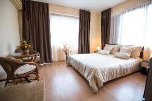 a bedroom with a bed and a chair and windows at Complex Apolon in Nesebar +107 photos