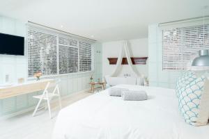 1 dormitorio con cama blanca, escritorio y ventanas en Casa Legado, en Bogotá