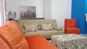 a living room with a couch and an orange chair at Condominios La Ronda in Tegucigalpa