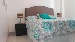 德古西加巴的住宿－Condominios La Ronda，一间卧室配有一张床和一个带床罩的床头柜。