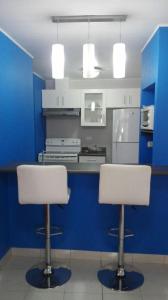 a kitchen with two white chairs and a blue wall at Condominios La Ronda in Tegucigalpa