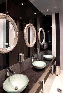 La salle de bains est pourvue de 3 lavabos et de miroirs sur un comptoir. dans l'établissement Pałac Domaniowski, à Wieniawa