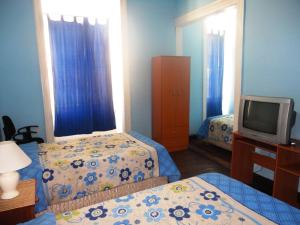 a hotel room with two beds and a television at Hotel Garden in Valparaíso