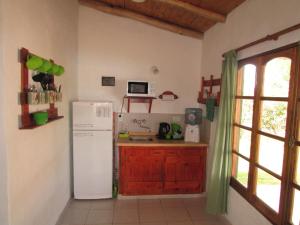 a kitchen with a white refrigerator and a window at Cabañas Las Bahienses in San Rafael