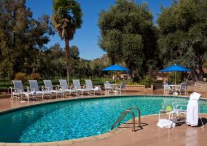 a swimming pool with chairs and blue umbrellas at Singing Hills Golf Resort at Sycuan in El Cajon