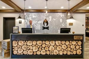 a man standing in front of a store with a pile of logs at Canalta Lodge in Banff