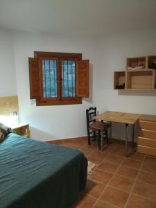 Un dormitorio con una cama, un escritorio y una mesa. en Cortijo El Cerrillo, en Granada