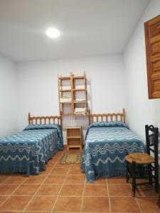 a bedroom with two beds and a tiled floor at Cortijo El Cerrillo in Granada