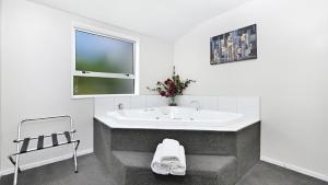 a white bathroom with a sink and a chair at Arthur's Court Motor Lodge in Christchurch +50 photos