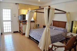 a bedroom with a bed and a table and a television at Surfside Boracay Resort in Boracay