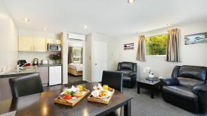 a living room with a table and chairs and a kitchen at Arthur's Court Motor Lodge in Christchurch