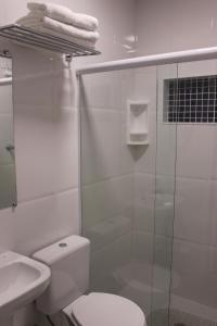 y baño blanco con aseo y ducha. en Pousada Suisse, en Campos do Jordão