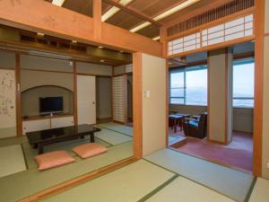 Habitación con sala de estar con mesa y TV. en Ikaho Grand Hotel, en Shibukawa