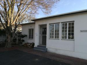 a white house with a tree in front of it at Paarl Backpackers in Paarl