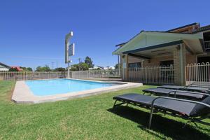 a swimming pool in a yard with two lounge chairs next to it at Atlas Motel in Dubbo